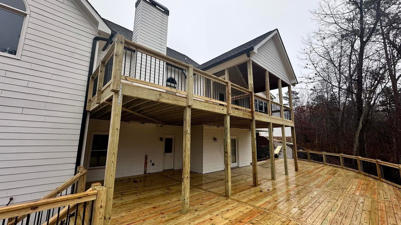 Multi-level wood deck with black metal railings attached to a residential home by Horizon Home Services